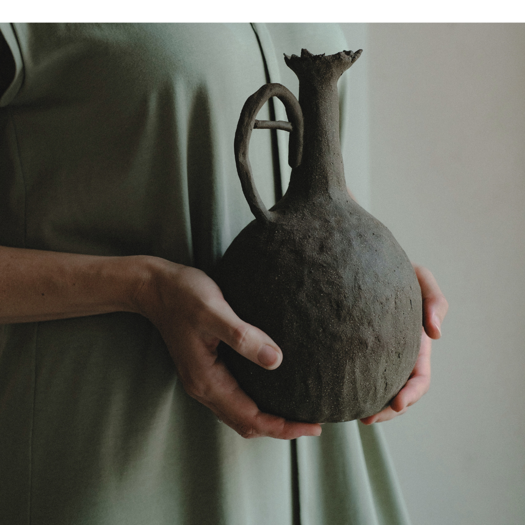 person in mint dress holding a rustic clay jug