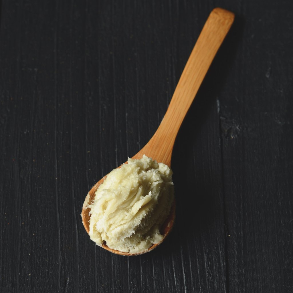 scoop of shea butter on wooden spoon with black background