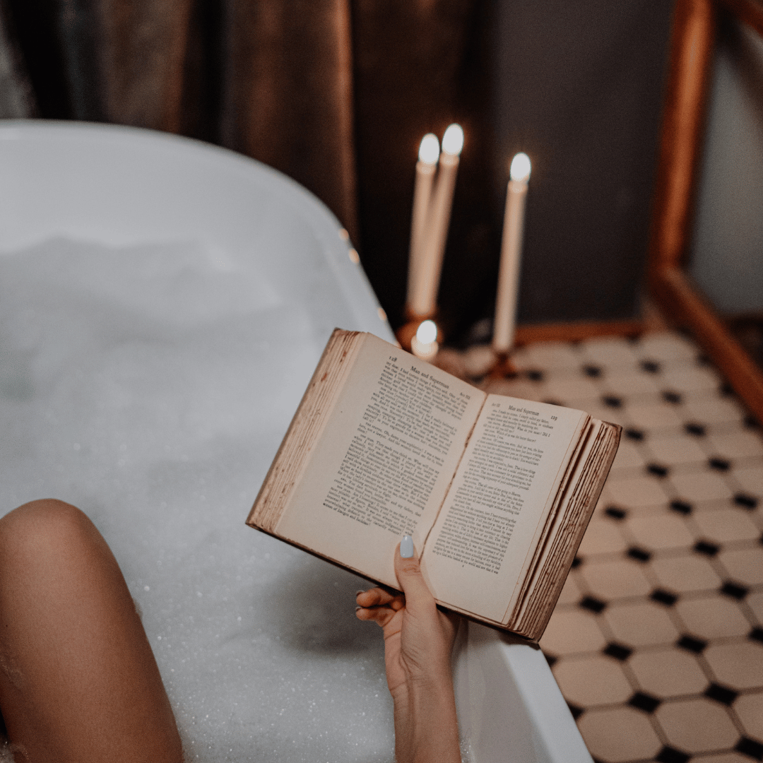 person in bubble bath old fashioned tub with book and candles