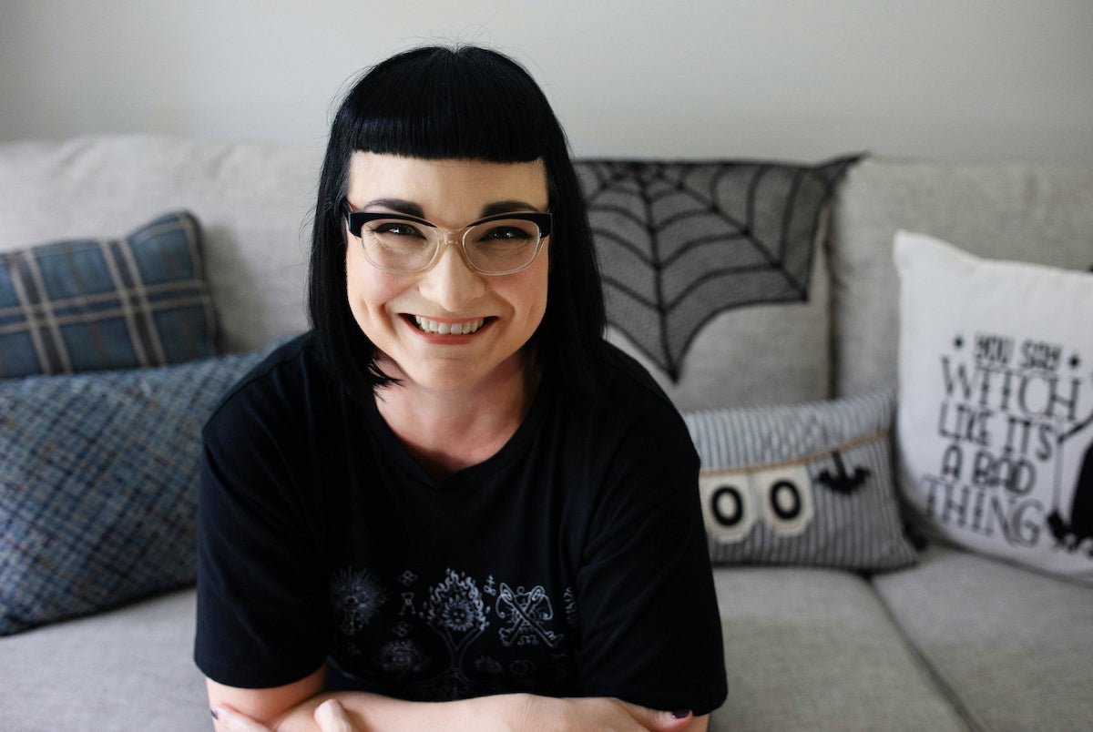 aliya hutchison of soap cult australia sitting on lounge with cobweb cloth and halloween cushions