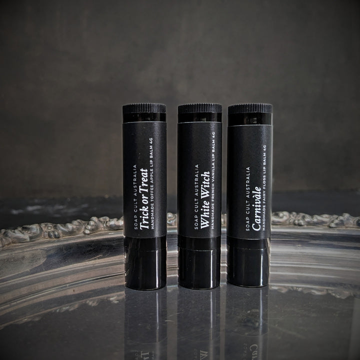 soap cult australia lip balms in recyclable black tubes on ornate silver tray on mottled black surface