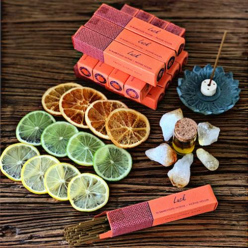 boxes of orange luck incense with slices of citrus fruit and citrine crystals