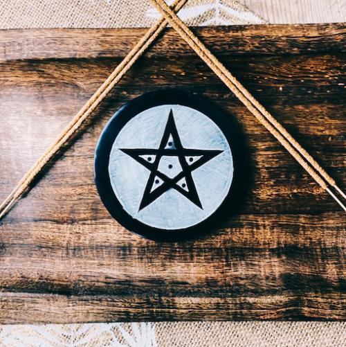 black and white soapstone pentagram round altar tile and incense burner on timber surface with incense sticks