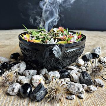 glossy black hecate offering bowl with botanicals stones and witches burrs