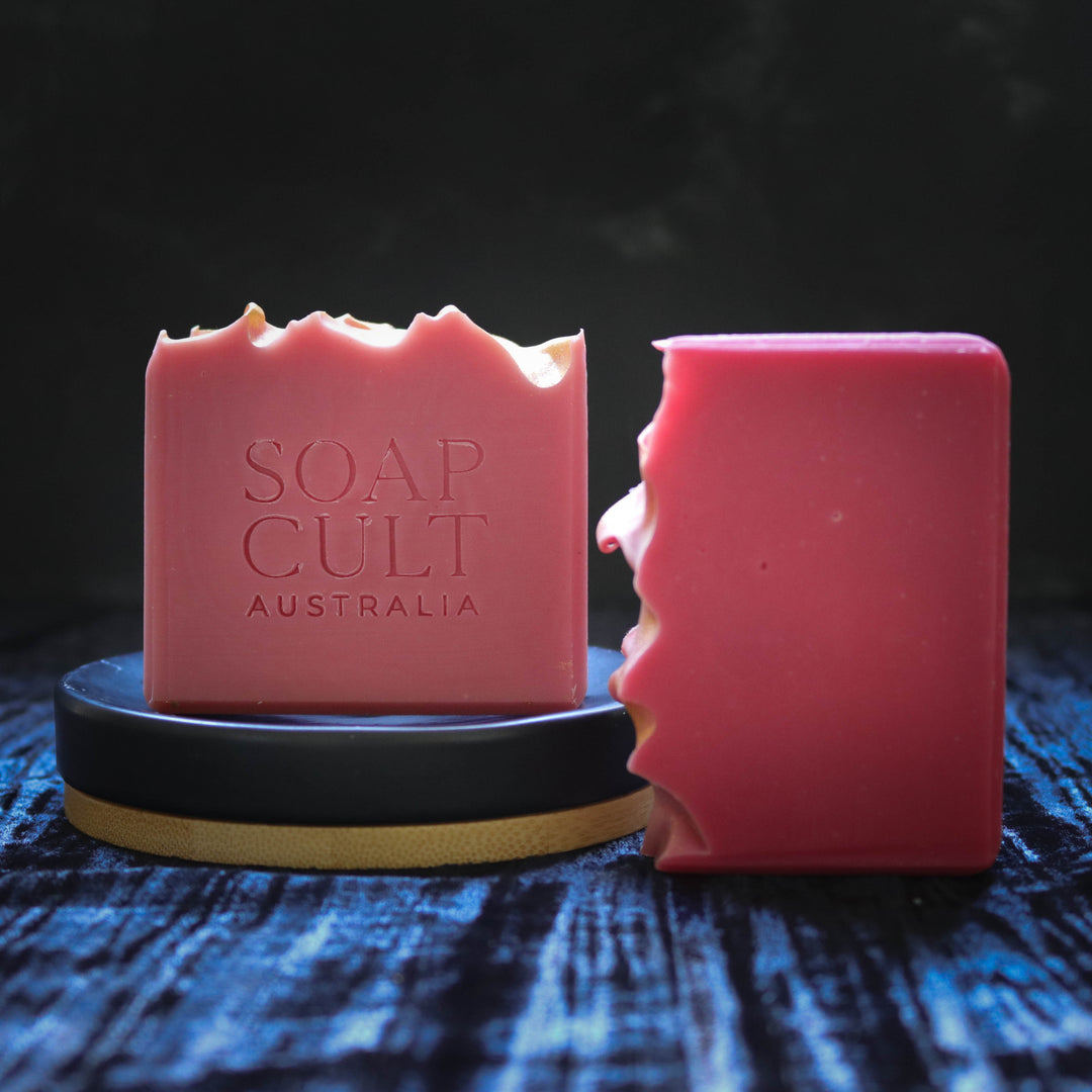 two bars of red soap with wavy top and gold dusting on soap dish with velvet