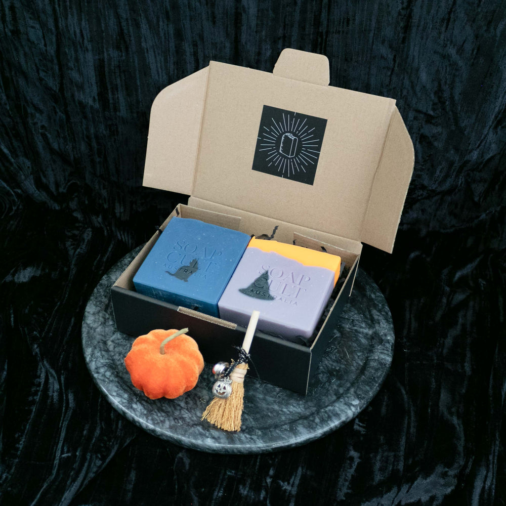 blue purple and orange halloween soap in gift box with decorative pumpkin and broomstick