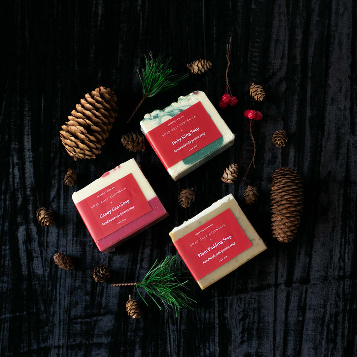 three christmas soap surrounded by pine cones and faux tree and berries